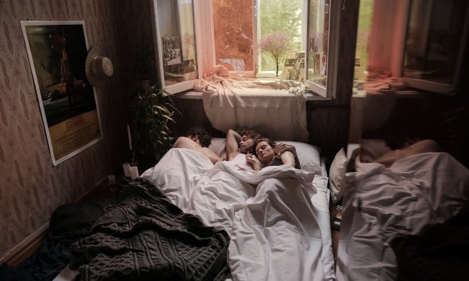 skupina ljudi v postelji pri odprtem oknu
